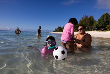 Children playing near adults in the shallows of Rarotonga coastal waters