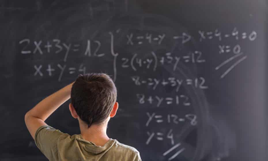 Child at blackboard with maths problem.