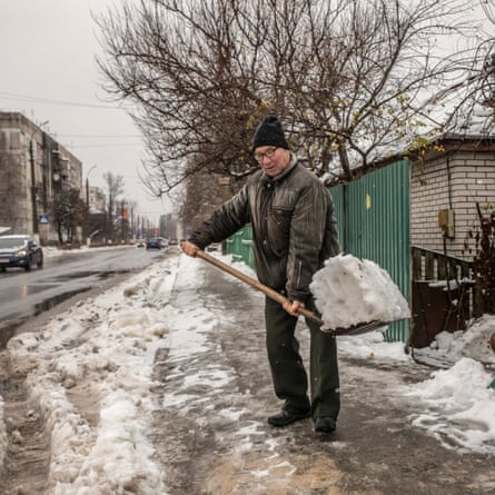 Vasyl, a resident of Borodianka, shovels snow in front of his house