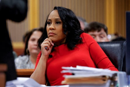 Fani Willis sits at a desk containing a pile of papers in a courtroom