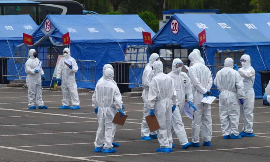 Government workers in protective clothing outside a tent used to coordinate transporting people from Wuhan to quarantine in Beijing.