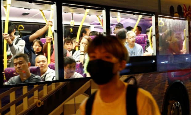Bus passengers watch a protester walking along the main road from Hong Kong international airport.