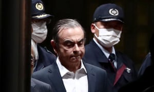 Former Nissan chairman Carlos Ghosn escorted as he walks out of the Tokyo Detention House following his release on bail in April 2019.