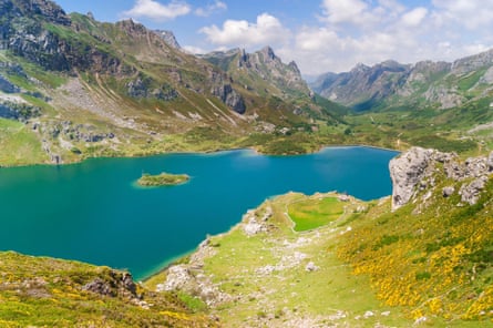 A blue lake surrounded by grass and mountains
