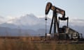A pump jack on the landscape with mountains in the distance behind
