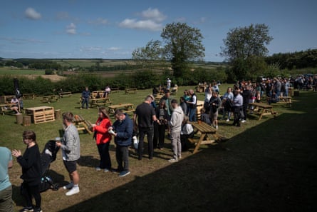 People stand in a queue waiting for the pub to open