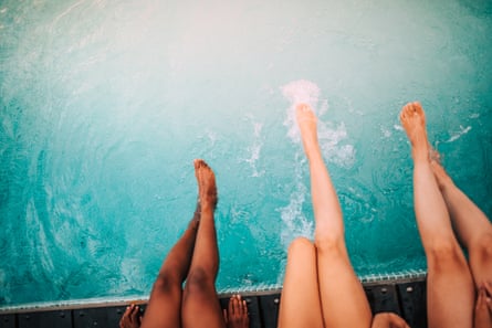 Three friends splashing their legs in a pool