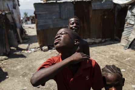 Three young boys among corrugated shacks in a shanty town in Haiti