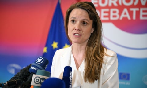 Woman speaks at microphone with EU flag behind