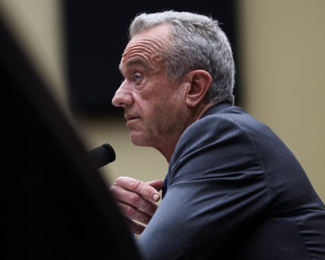 side profile of man in a suit sitting behind a microphone