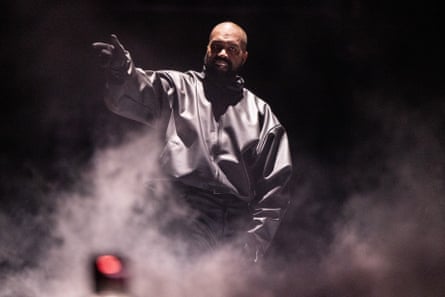 Kanye West gestures while performing onstagein a cloud of smoke or dry ice