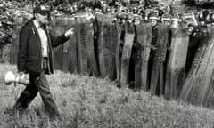 Arthur Scargill, carrying a loudhailer, walks past  police with riot shields