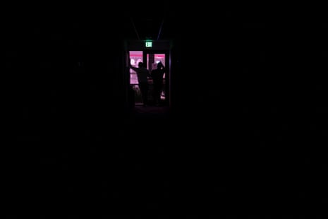 People look out the window of a dark hotel lobby.