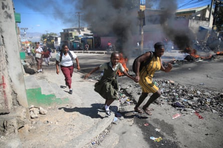 A mother and daughter run past a roadblock in Port-au-Prince, Haiti, in late January.