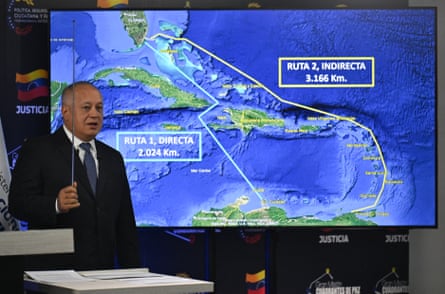 A man standing at a lectern in front of a screen showing a map of the Caribbean