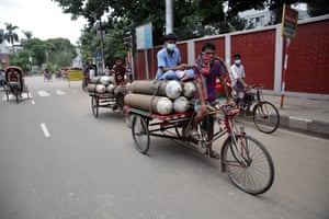 Day labourers transport oxygen cylinders to hospital on a pedal-powered van