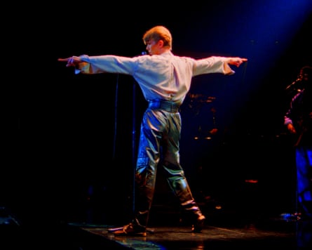 Bowie standing with his arms extended in a T shape onstage on the Isolar II tour