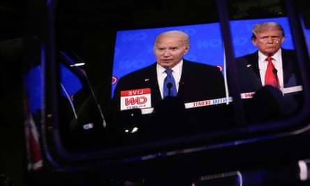 A car door reflects Joe Biden and Donald Trump, both men wearing suits and looking ahead