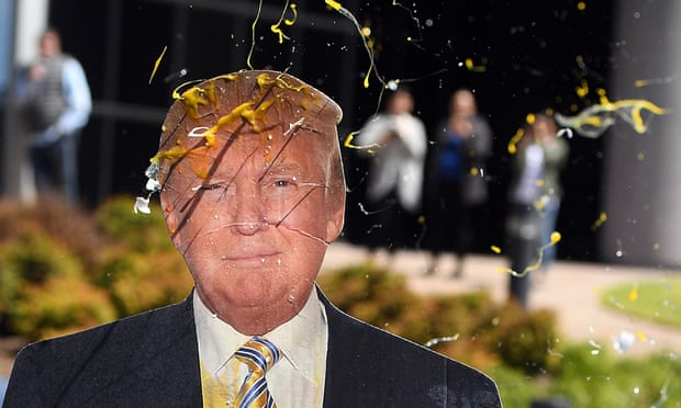An egg is thrown at a cardboard cutout of  Donald Trump