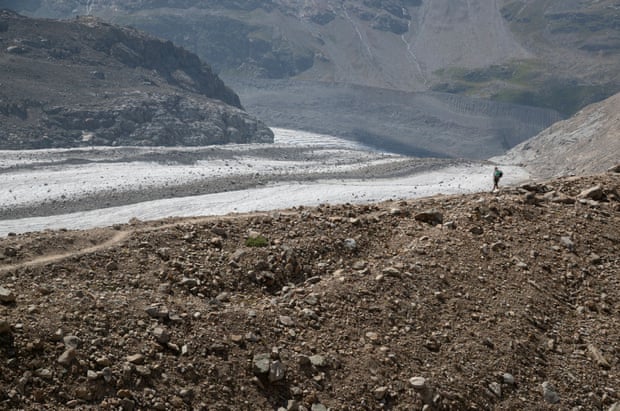 A hiker walks on a border moraine of the Pers Glacier