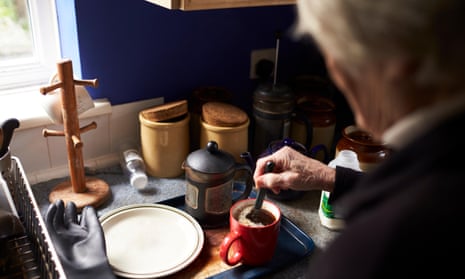 Older woman makes a pot of coffee in a kitchen.