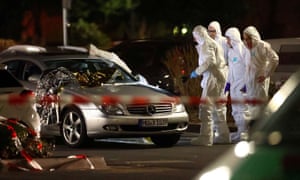 Forensic experts work around a damaged car after the shooting.
