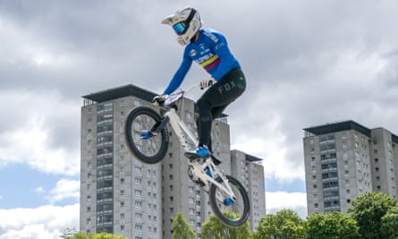 A BMX rider, with tower blocks in the background.