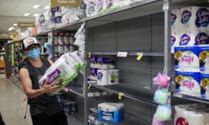 A man wearing a face mask buys toilet tissues at a supermarket in Auckland on Sunday. Three community cases of Covid reported on Sunday sent New Zealand’s largest city into level three restrictions.