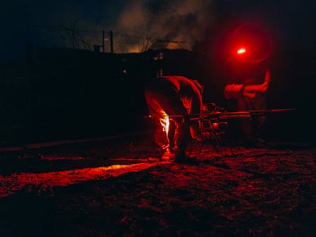 People work on machinery at night, illuminated by a red light