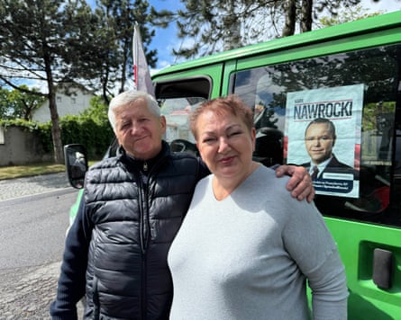 A couple in Poland, him with his arm around her standing in front of a green van.