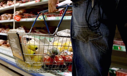 A person holding a shopping basket in a supermarket.