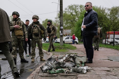 Military members stand near the collected remains of missiles, displayed on the pavement, which fell in Chernihiv on Wednesday.