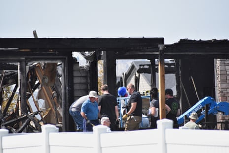 investigators work at the scene of a burned home
