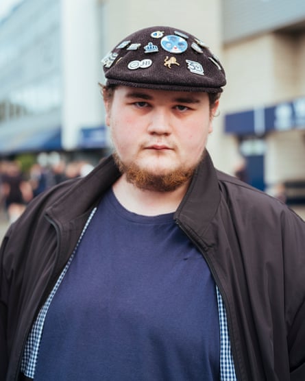 Young man in flat cap with Millwall badges outside the Den