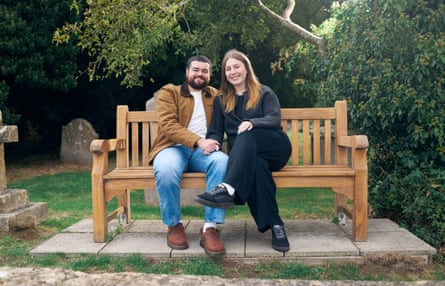 Sophie and Sam sit on their favourite bench in a churchyard with gravestones and bushes as a backdrop.