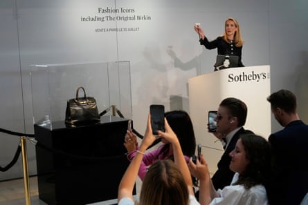 People take photos of a black leather bag in a glass case during a Sotheby’s auction