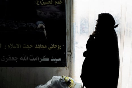 A woman waits for permission to cross back into Iran at the Shalamjah border crossing with Iran in southeastern Iraq
