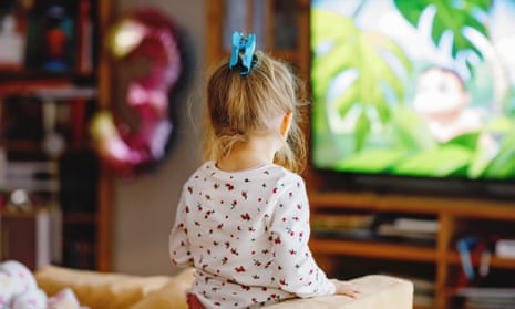 A toddler girl watching TV at home