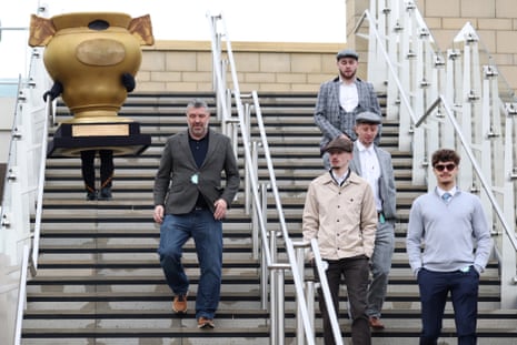 A man dressed as the Gold Cup trophy descends the stairs with other racegoers at Cheltenham.