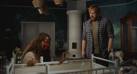 Seidi Haarla, blood-covered, kneels by a crib as Rupert Grint watches with concern