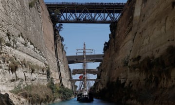 A three-masted ship sails between steep cliffs on a canal