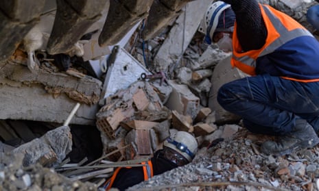 two men in high-vis jackets in rubble