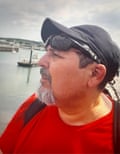 Headshot of Claudio Aquilino wearing cap with river and coast behind him