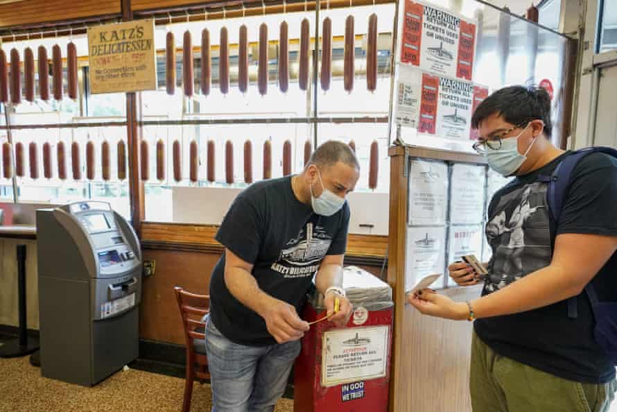 An employee at Kat’s Deli checks a customer’s proof of vaccination