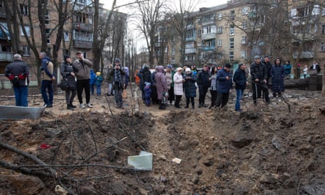 Los residentes locales se paran cerca de un cráter después de un cohete en Kyiv, Ucrania, el 1 de enero.