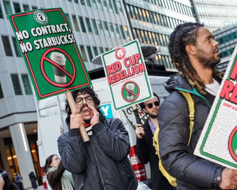 people chant while holding signs that read 'no contract, no Starbucks' and 'red cup rebellion'