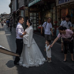 A couple pose for their pre-wedding photos as people pass by in the Hutong neighbourhood in Beijing