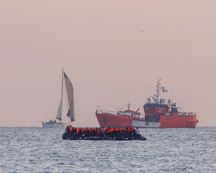 A crowded small boat in the foreground with two other vessels in the distance