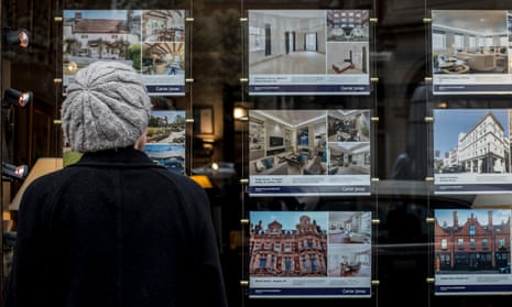 a woman looks at homes for sale through an estate agent's window