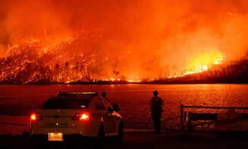 Law enforcement members watch a red sky filled with embers as the Thompson fire burns